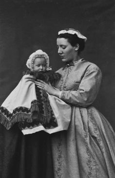 an old black and white photo of a woman holding a doll