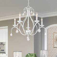 a white chandelier hanging from the ceiling in a room with grey walls and furniture