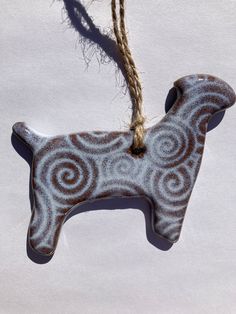 a ceramic dog ornament hanging from a rope on a white background with swirls