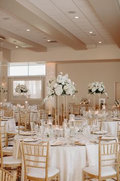 the tables are set up with white flowers and gold chairs for an elegant wedding reception