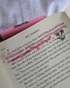 an open book with writing on it and a pink pen next to the book's page