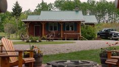 there is a small cabin in the back yard with chairs and fire pit on the lawn