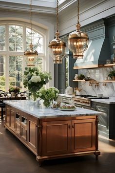 a large kitchen with marble counter tops and gold pendant lights hanging from the ceiling over the island