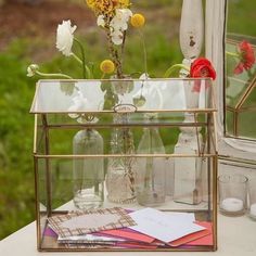 a glass vase with flowers in it sitting on a table next to some candles and other items