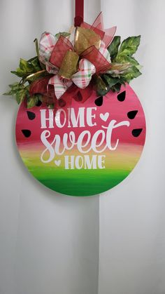 a wooden sign that says home sweet home hanging on a wall with a ribbon and bow