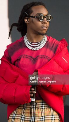 a woman wearing sunglasses and a red jacket is standing with her arms folded in front of her