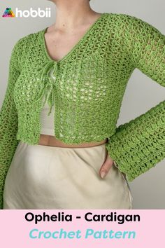 a woman wearing a green crochet cardigan with her hands on her hips