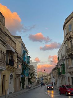 cars are driving down the street in front of some buildings at sunset or sunrise time