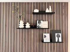 two black shelves with books and vases on them in front of a striped wall