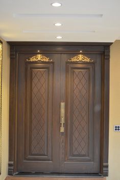 two wooden doors with ornate carvings on them in front of a wall and carpeted floor