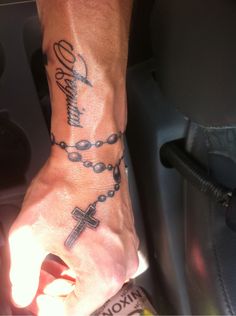 a person with a rosary tattoo on their arm and wrist is sitting in a car