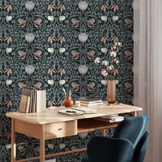 a desk and chair in front of a wallpapered background with flowers on it