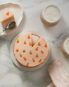 a cake with carrots on it sitting on a plate next to two cups and spoons