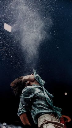 a man is blowing out some white powder on his face and head as he looks up at the sky