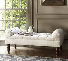 a bed with white linens and pillows on it, in front of a window