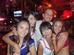 a group of young people standing next to each other in front of a neon bar