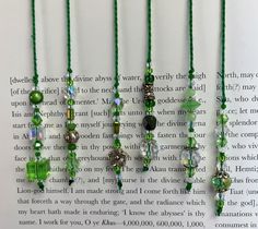 four green necklaces are hanging from a book with the pages in front of them