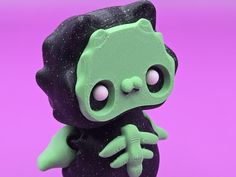 a close up of a small toy on a purple background with black and green speckles