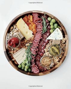 a wooden bowl filled with meats, cheese and crackers on top of it