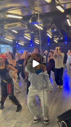 a group of people dancing in a room with lights on the ceiling and one person holding his head up