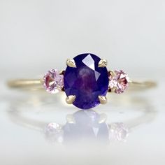 an oval shaped purple sapphire and pink tourmaline ring with three diamonds on each side