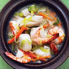 shrimp, scallops and carrots are in a bowl on a green cloth