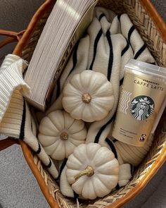 a basket filled with white pumpkins next to a cup of starbucks latte coffee