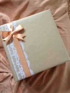 a gift wrapped in brown paper with a bow on it's side sitting on a bed