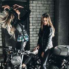 two beautiful young women standing next to motorcycles