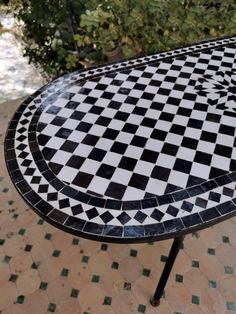 a black and white checkered table on a tiled floor with trees in the background