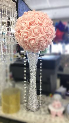 a vase filled with pink roses on top of a table next to a glass beaded chandelier