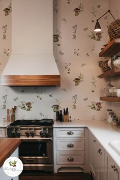 a stove top oven sitting inside of a kitchen next to a wall papered with flowers