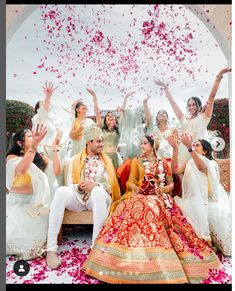 the bride and groom are surrounded by confetti as they sit on a bench