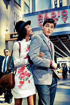 a man and woman standing in front of a radio city music building with their arms around each other