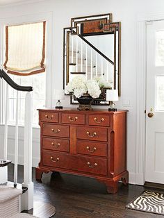 a wooden dresser sitting in front of a mirror on top of a stair case next to a white door