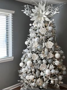 a white christmas tree decorated with silver ornaments