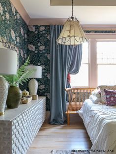 a bedroom with floral wallpaper and blue curtains