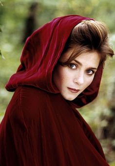 a woman in a red cloak is posing for the camera with her eyes wide open