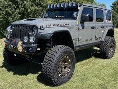 a gray jeep parked in the grass near trees