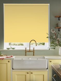 a yellow roller blind in a kitchen window above a white sink and dishwasher