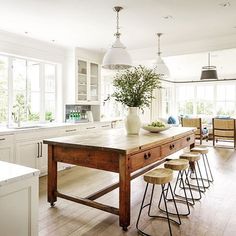 a kitchen island with stools in front of it and a potted plant on top