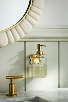 a bathroom sink with soap dispenser next to it and a mirror above it