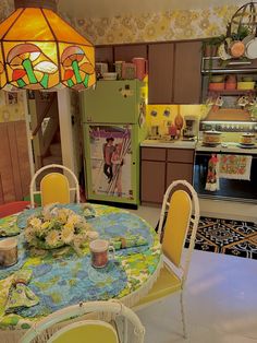 a dining room table with yellow chairs and a green refrigerator in the kitchen behind it