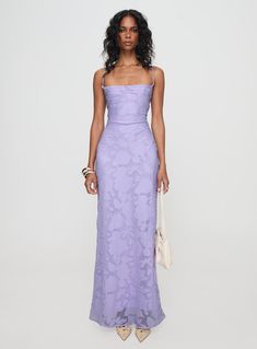 a woman in a long purple dress standing with her hands on her hips and looking off to the side