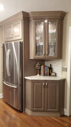 a kitchen with wooden floors and cabinets in the corner, along with a stainless steel refrigerator