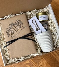 an open box containing a coffee mug, notepad and keychain