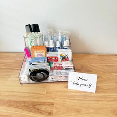 a wooden table topped with lots of different types of cosmetics and personal care items next to a sign