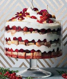 a layered cake with cherries on top and white frosting in a glass dish