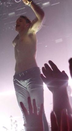 a man standing on top of a stage with his arms in the air while holding a bottle