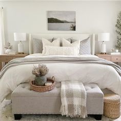 a bedroom with a large bed and white linens on the headboard, footstools and pillows